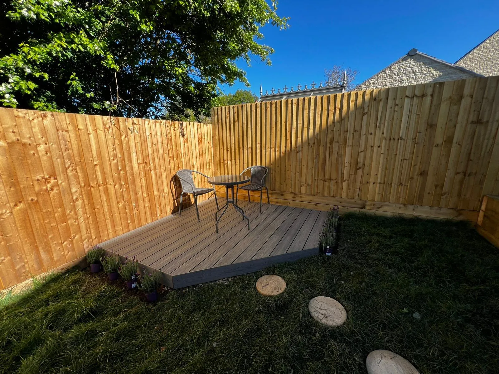 A wooden deck in a backyard with a table and chairs.